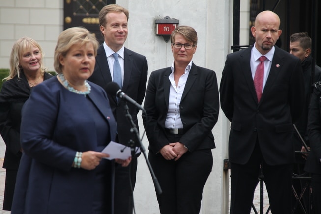 Erna Solberg holder en tale med politikere i bakgrunnen