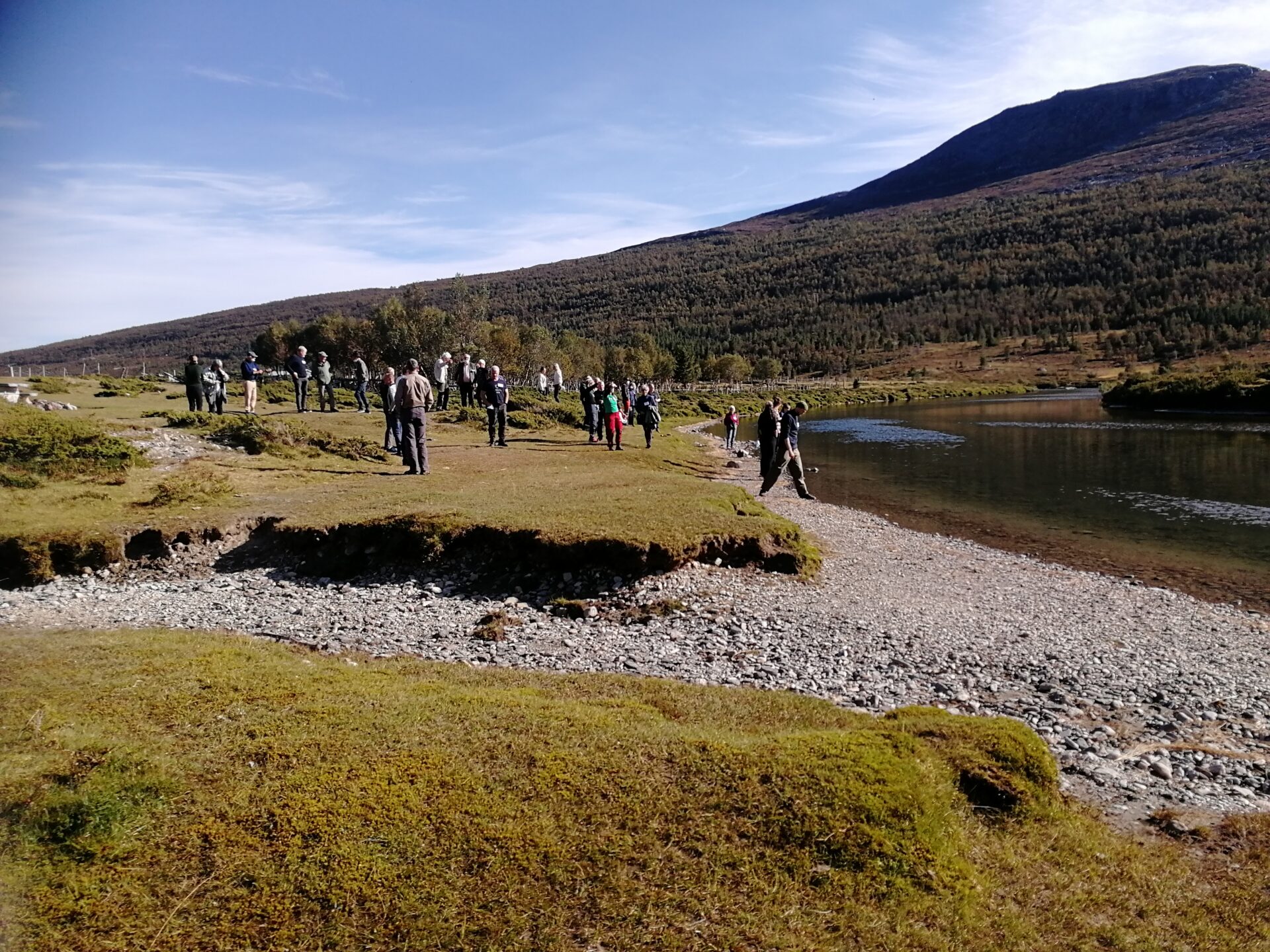 Landskap med et vassdrag. En gjeng tillitsvalgte er på guidet tur og ser på vannet.