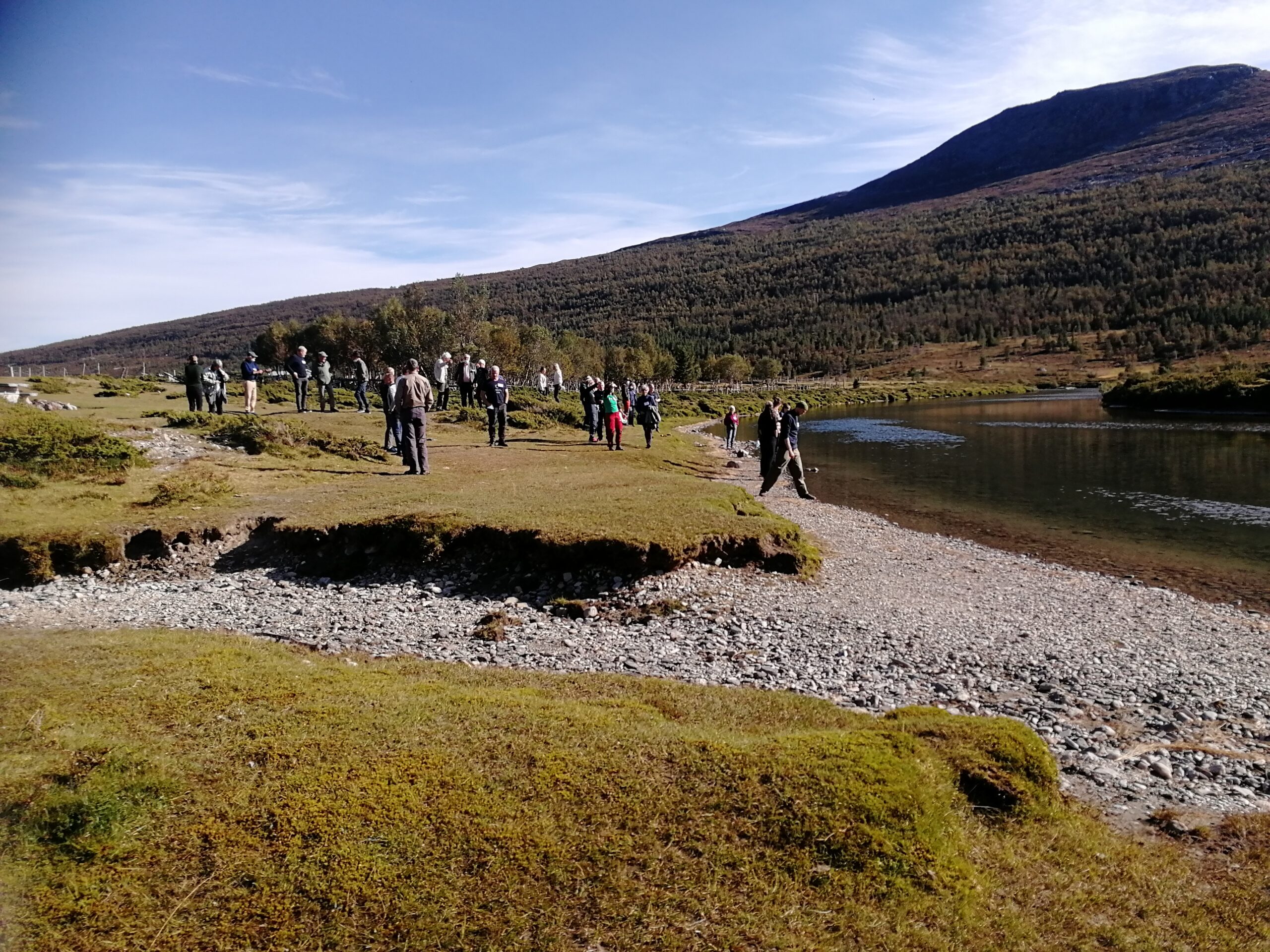 Landskap med et vassdrag. En gjeng tillitsvalgte er på guidet tur og ser på vannet.