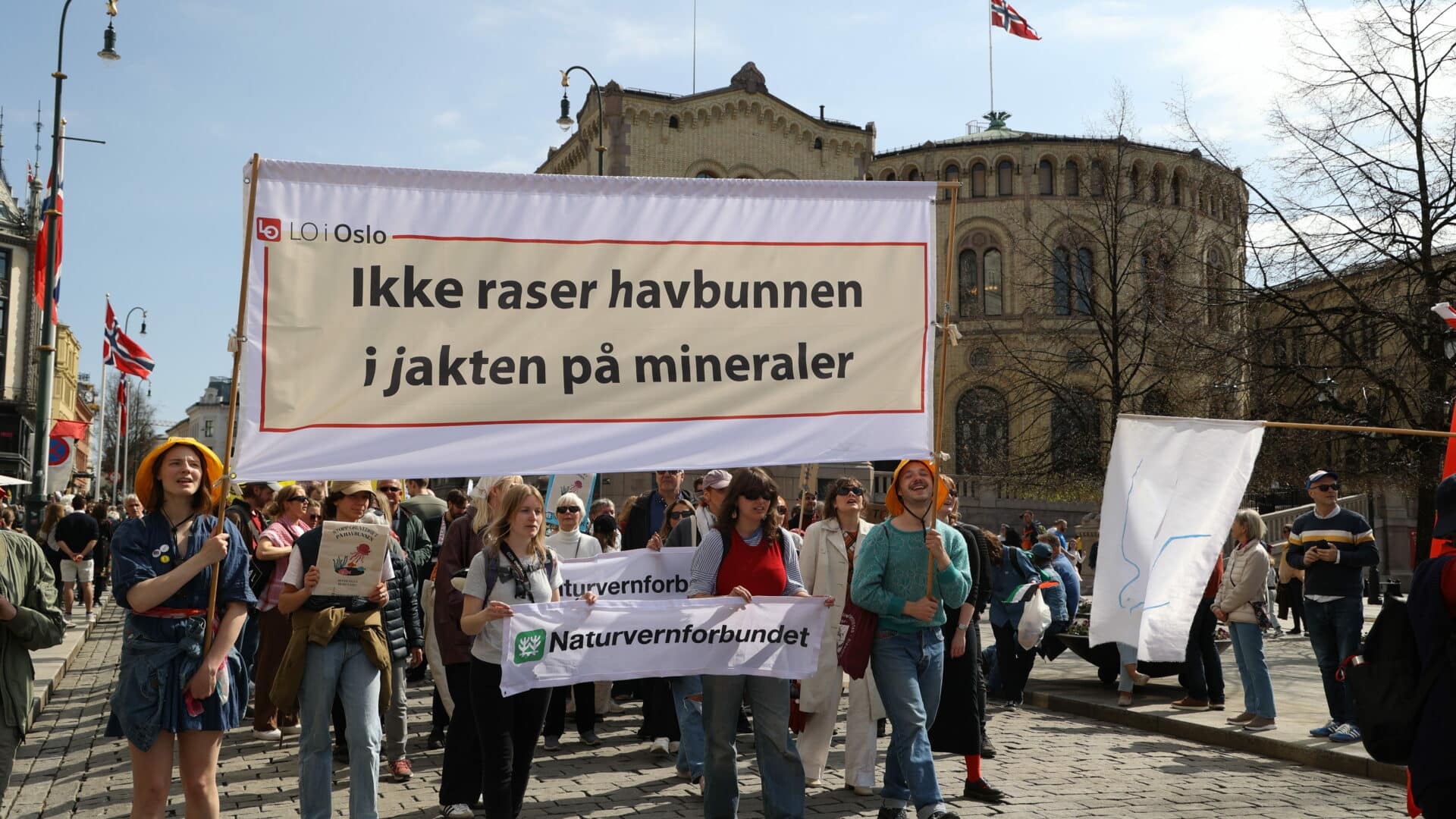 Mennesker går i 1.mai-tog og holder oppe parolen "Ikke raser havbunnen i jakten på mineraler" foran Stortinget.