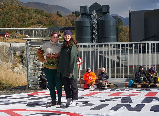 Pernille Bonnevie Hansen, leder i Naturvernforbundet, og Sigrid Hoddevik Losnegård, leder i Natur og Ungdom, foran Nordic Minings gruveanlegg ved Førdefjorden. I bakgrunnen er aksjonister fra Natur og Ungdom. Foto: Sebastian Goepel