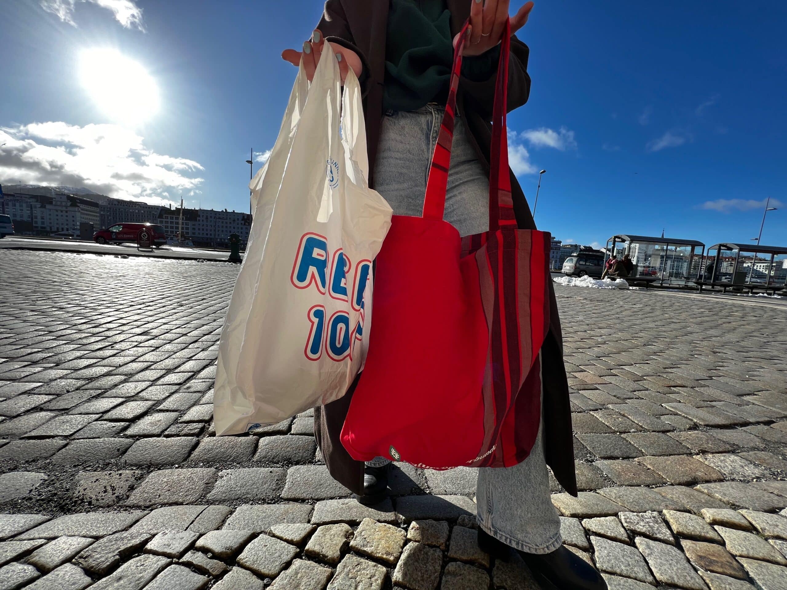 En person holder opp en plastpose og et bærenett