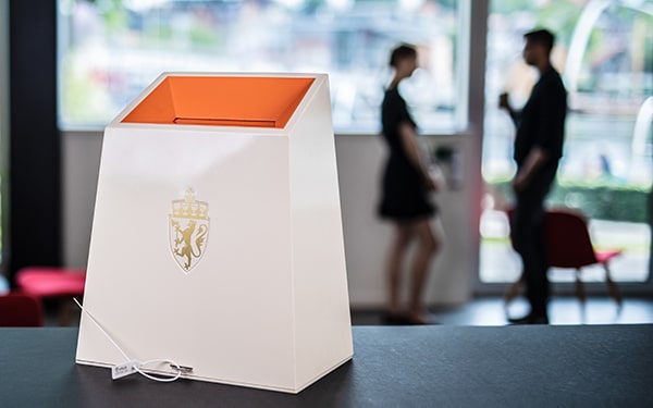 En valgurne med to personer som står bak