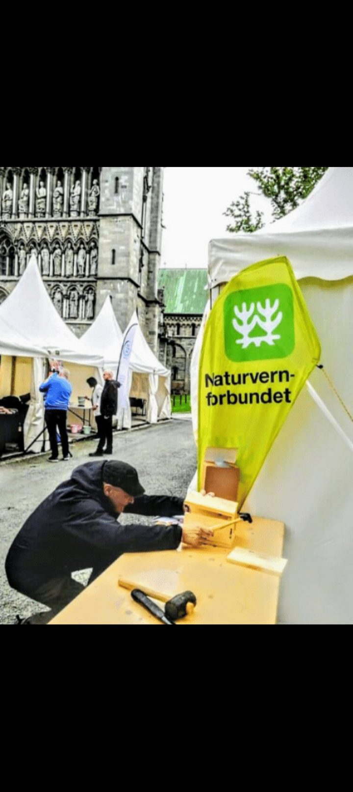 Mann gjør klar bod med grønn banner bak til fest.