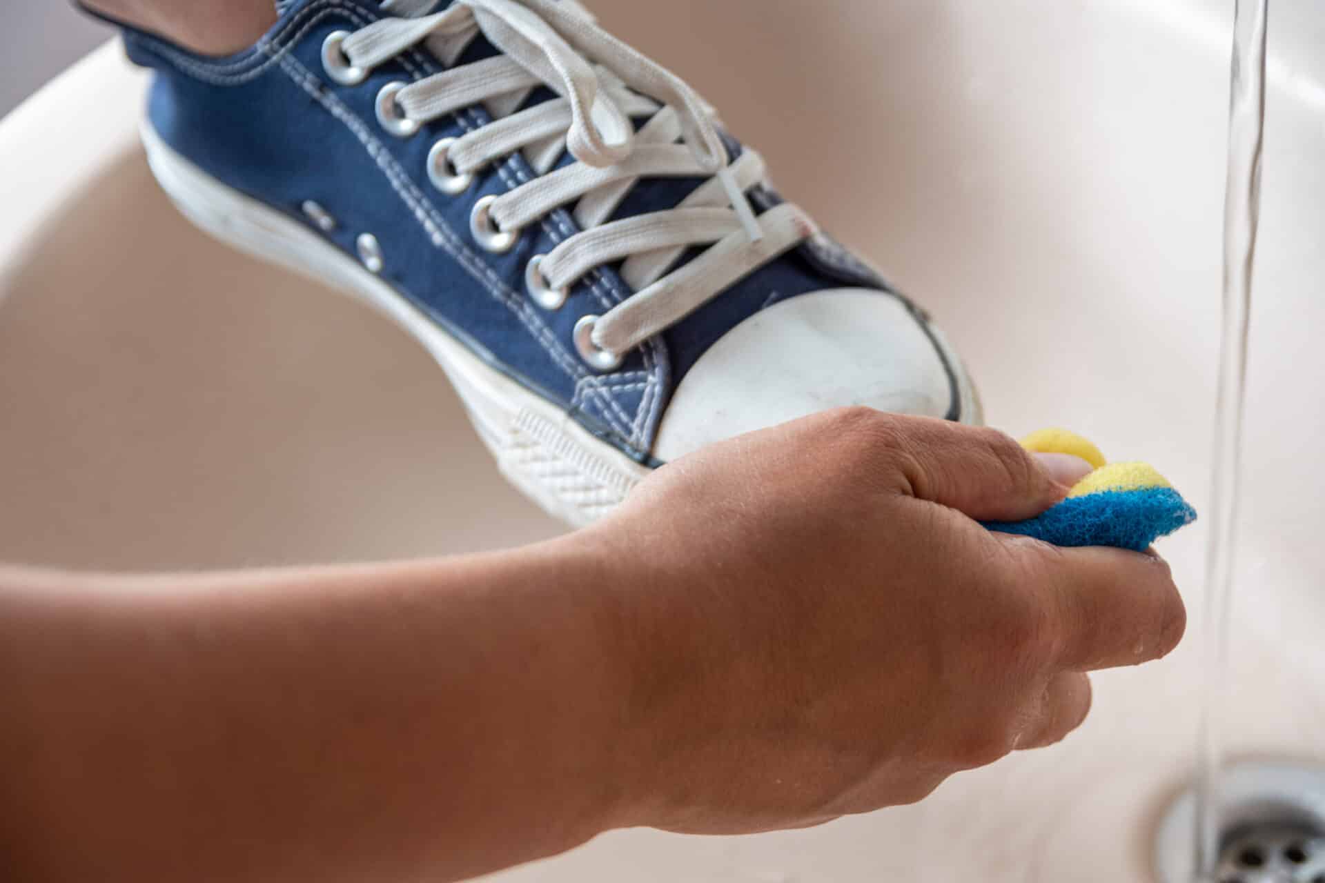 Nærbilde av en hånd som vasker sko med børste